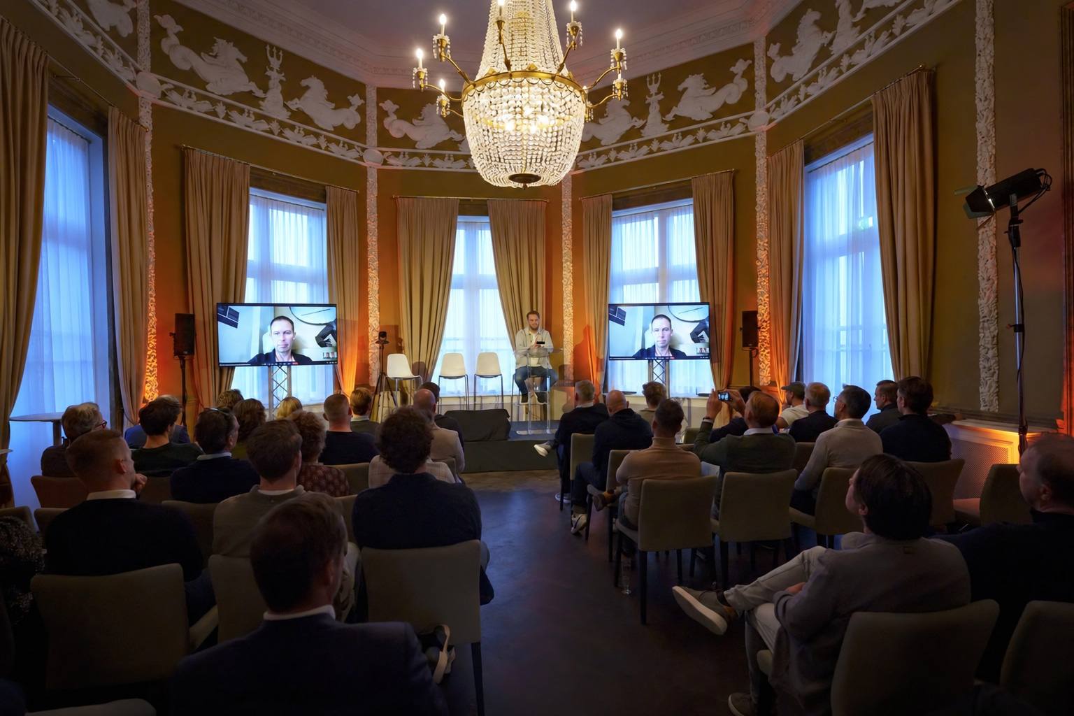 Volle zaal onder kroonluchters tijdens Connect in Paviljoen de Witte